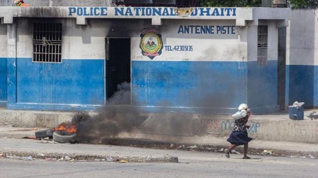 una mujer corre frente a un cuartel de la policía en Haití
