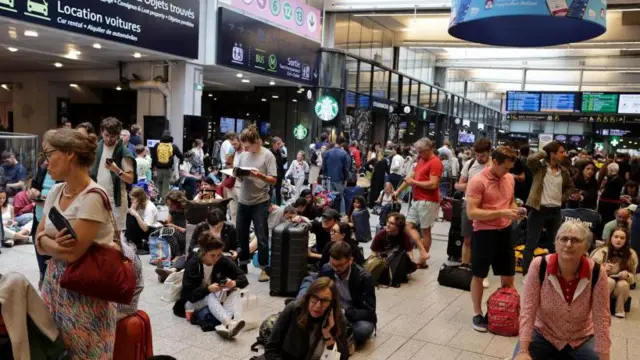 Los pasajeros esperan la salida de sus trenes en la estación de tren Gare Montparnasse en París.