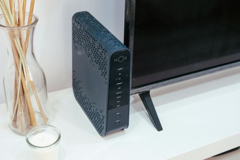Router WiFi blanco con luces encendidas en el salón de una casa, un ejemplo de dispositivo vulnerable a ataques remotos si no se asegura correctamente.