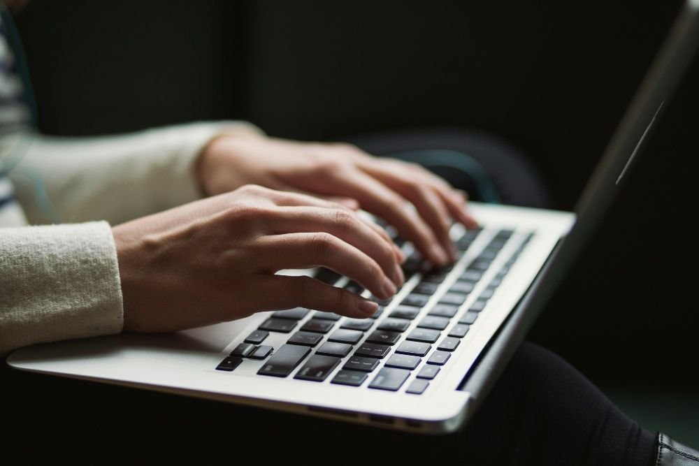 Persona tecleando en un portátil sin conexión a internet, intentando resolver un problema de red doméstica.