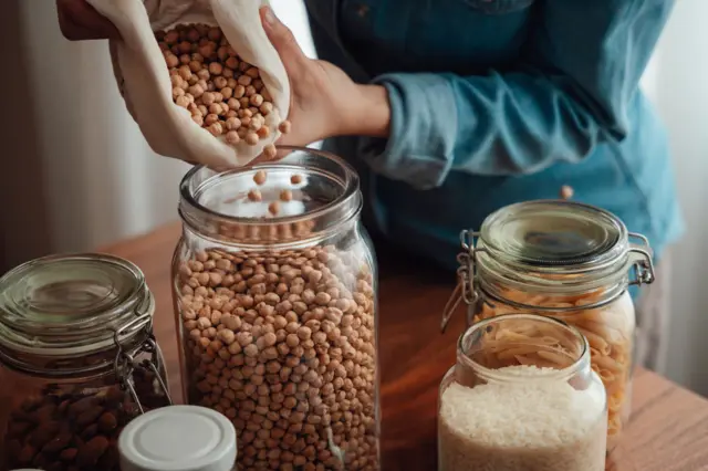 Una persona poniendo garbanzos en un frasco.