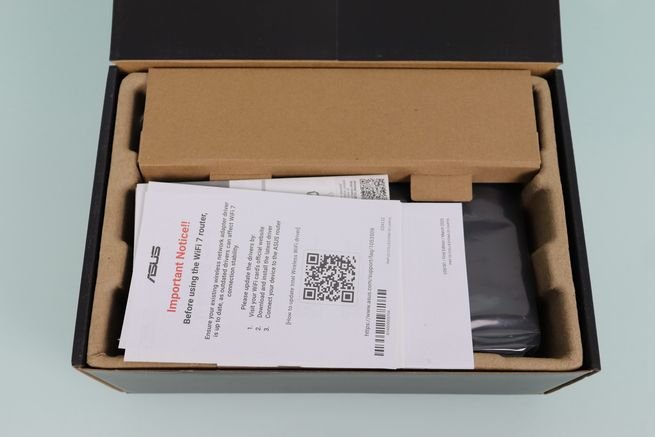 Interior de la caja del router ASUS RT-BE55 con la documentación y accesorios.