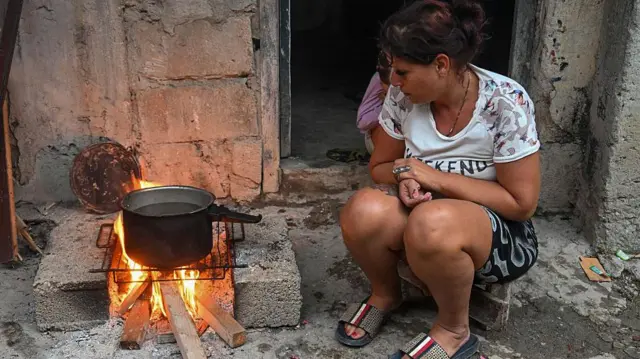Cubanos se ayudan a cocinar con ollas sobre carbón y leña.