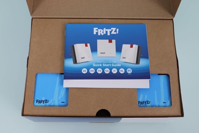 Interior de la caja del sistema Wi-Fi Mesh FRITZ!Mesh Set 1700 con la documentación y repetidores.