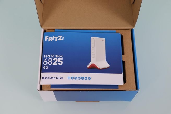 Caja abierta del router FRITZ!Box 6825 4G mostrando el manual de usuario y el embalaje de cartón interior.