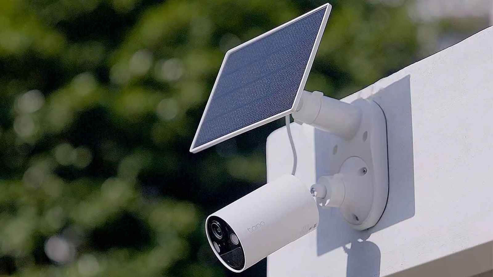 Cámara de seguridad exterior de color blanco instalada en una pared con un pequeño panel solar integrado en la parte superior.
