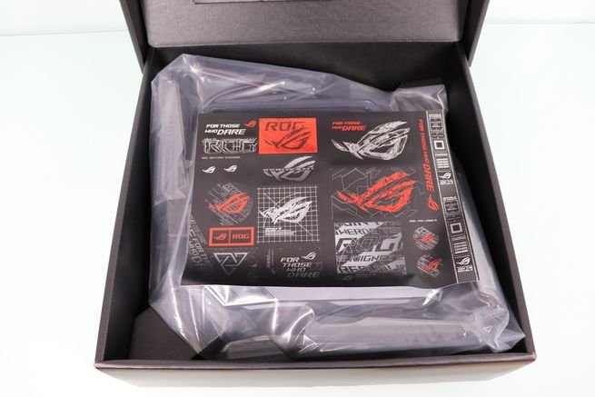 Interior de la caja del router ASUS GT-BN98 con una hoja de pegatinas de Republic of Gamers y el dispositivo protegido.